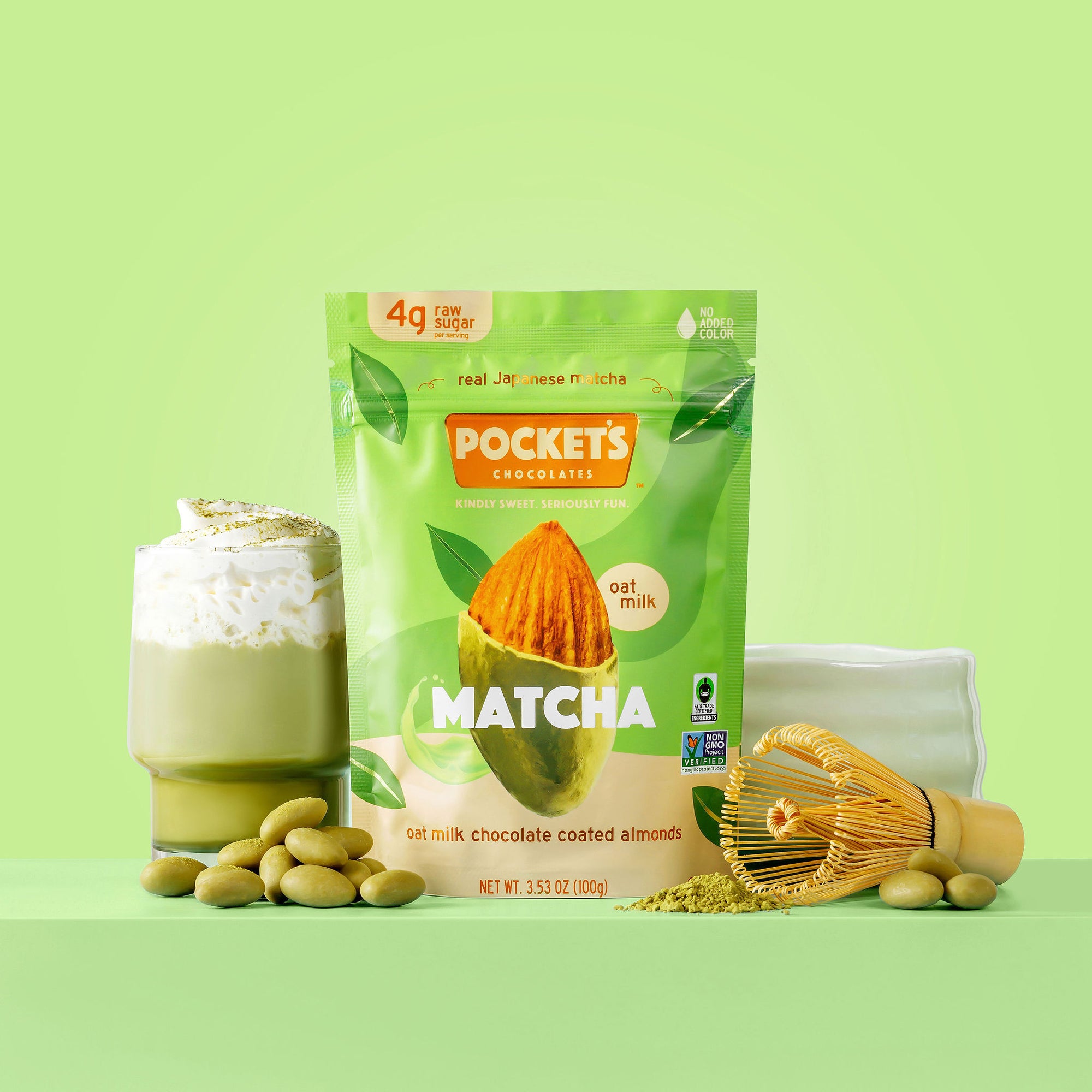 Matcha flavored oat milk chocolate coated almonds by Pocket's Chocolates, with a matcha drink and ingredients on display